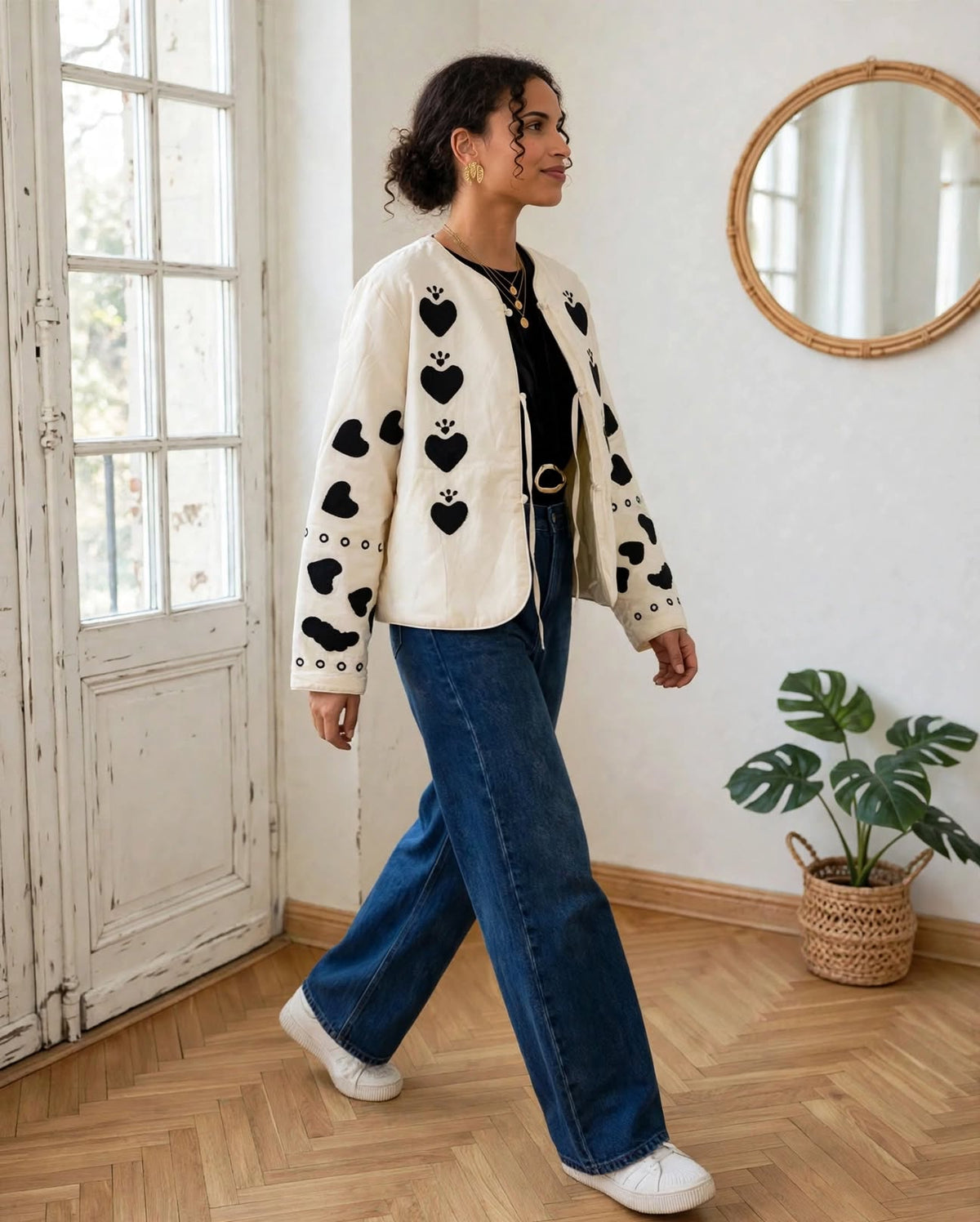 Veste Alma écrue à cœurs noirs portée ouverte sur un top noir avec un jean bleu.