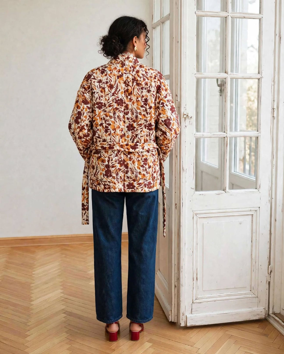 kimono Flora fleuri vu de dos, avec la ceinture à la taille et un jean bleu.